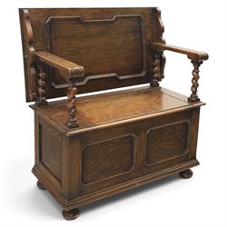 Early 20th century oak monks bench, panelled back converting to a table top, reeded armrests with barley twist uprights, hinged seat over panelled base supported on bun feet