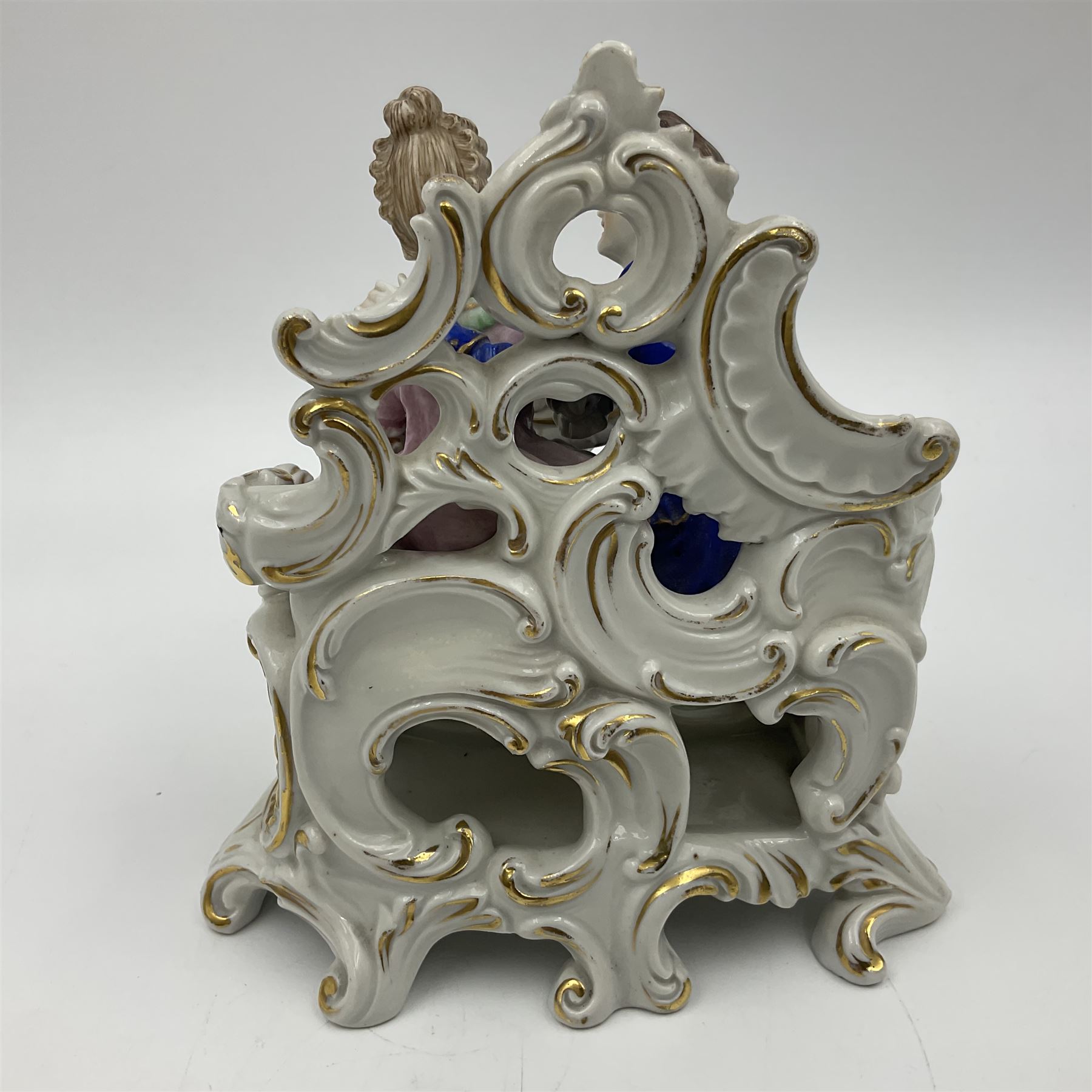 Figure group, probably Volkstedt, modelled as a courting couple seated before a table, the ornate bench and table conforming with and leading from the gilt heightened scrolling base, with blue painted mark beneath, H14.5cm
