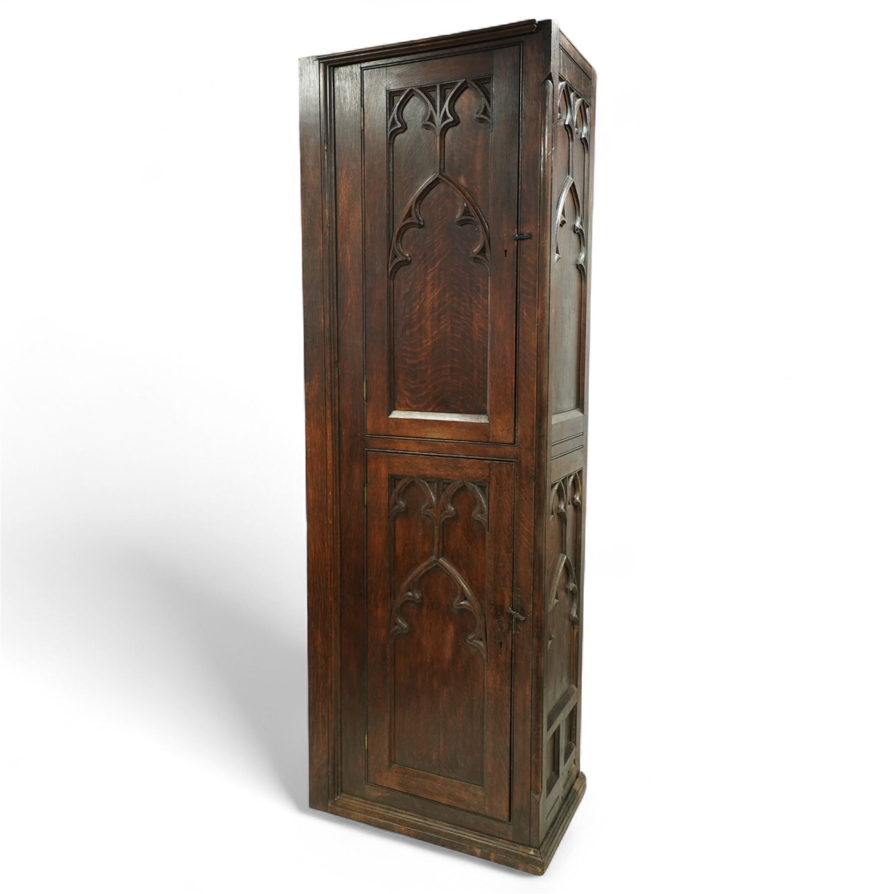 19th century Gothic Revival oak Sacristy vestment cupboard of tall proportions, fitted with two ecclesiastical trefoil moulded panelled doors enclosing four shelves, flanked by a chamfered corner, the side panelled and moulded with matching sacristic architectural mouldings, on skirted base