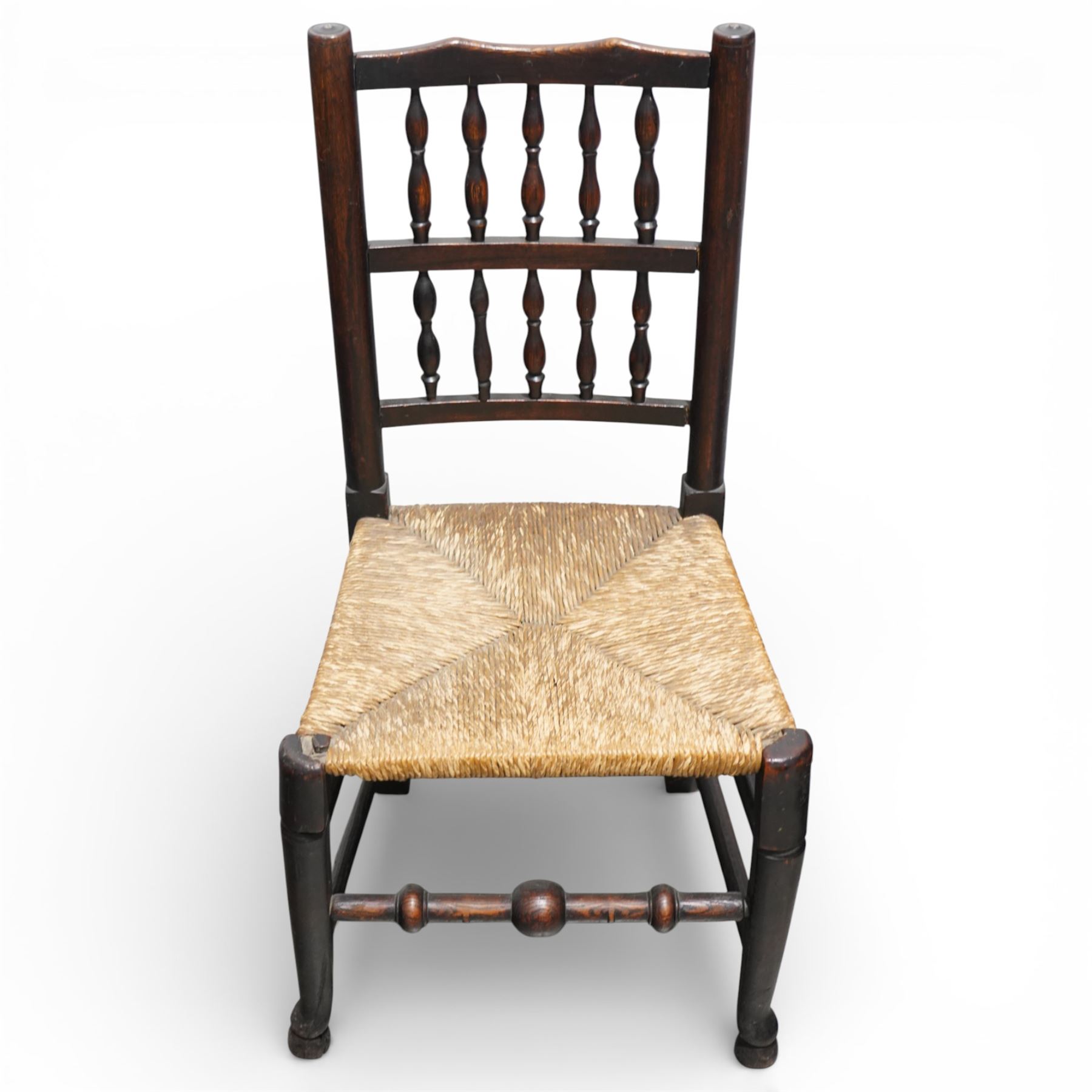 Set of five 19th century elm spindle back chairs, with shaped crest rails above double rows of turned spindles, rush seats, turned legs joined by stretchers supported on turned pad feet