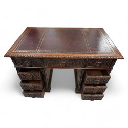 Victorian carved oak twin pedestal desk, moulded and foliate carved rectangular top with leather inset, fitted with nine drawers, each carved with scrolling foliage and lion mask handles, on skirted base 