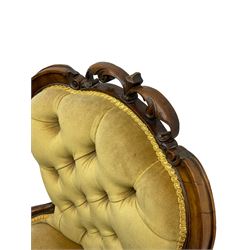 Victorian walnut nursing chair, the shaped cresting rail carved and pieced with foliate decoration, upholstered in green fabric, the apron with carved strapwork decoration, on cabriole front feet with brass castors
