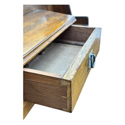 Early 20th century Arts and Crafts oak dressing chest, the arched mirror flanked by floral marquetry inlaid uprights above a shelf and drawer, over three long drawers with square hammered metal plates and circular pulls, on slender supports with castors
