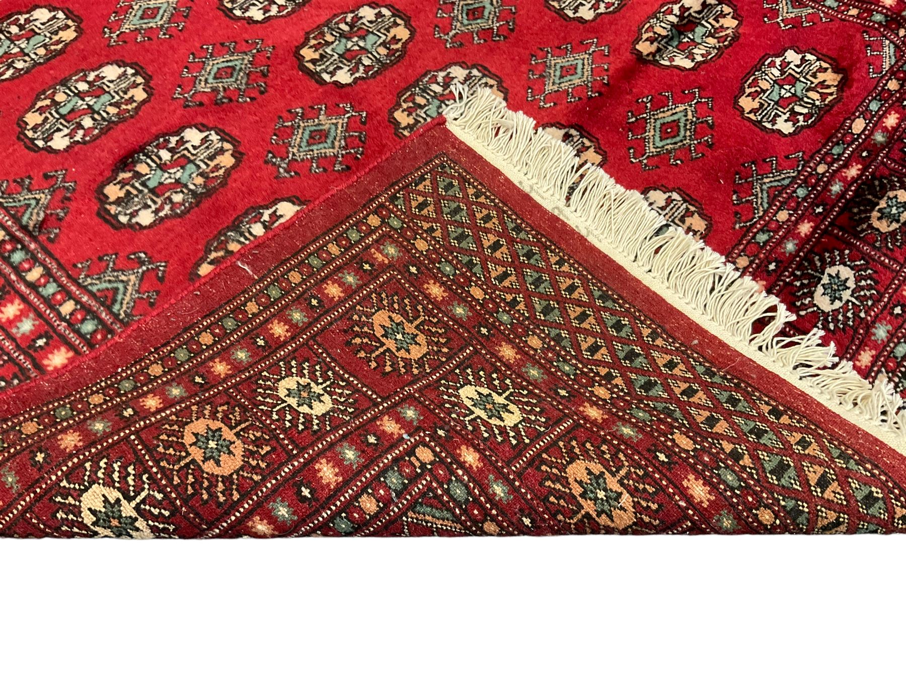 Persian Bokhara crimson ground rug, the field decorated with repeating Gul motifs and lozenges, the multi-band border with stylised plant motifs with black outlines