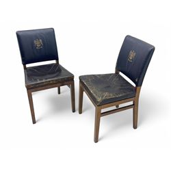 Pair of mid-20th century hardwood chairs associated with the Company of Cutlers in Hallamshire, Sheffield, each featuring a squared frame and black vinyl upholstery, the back emblazoned with the guild’s gilt coat of arms and motto “Pour Y Parvenir a Bonne Foi” (To Succeed through Honest Endeavour)