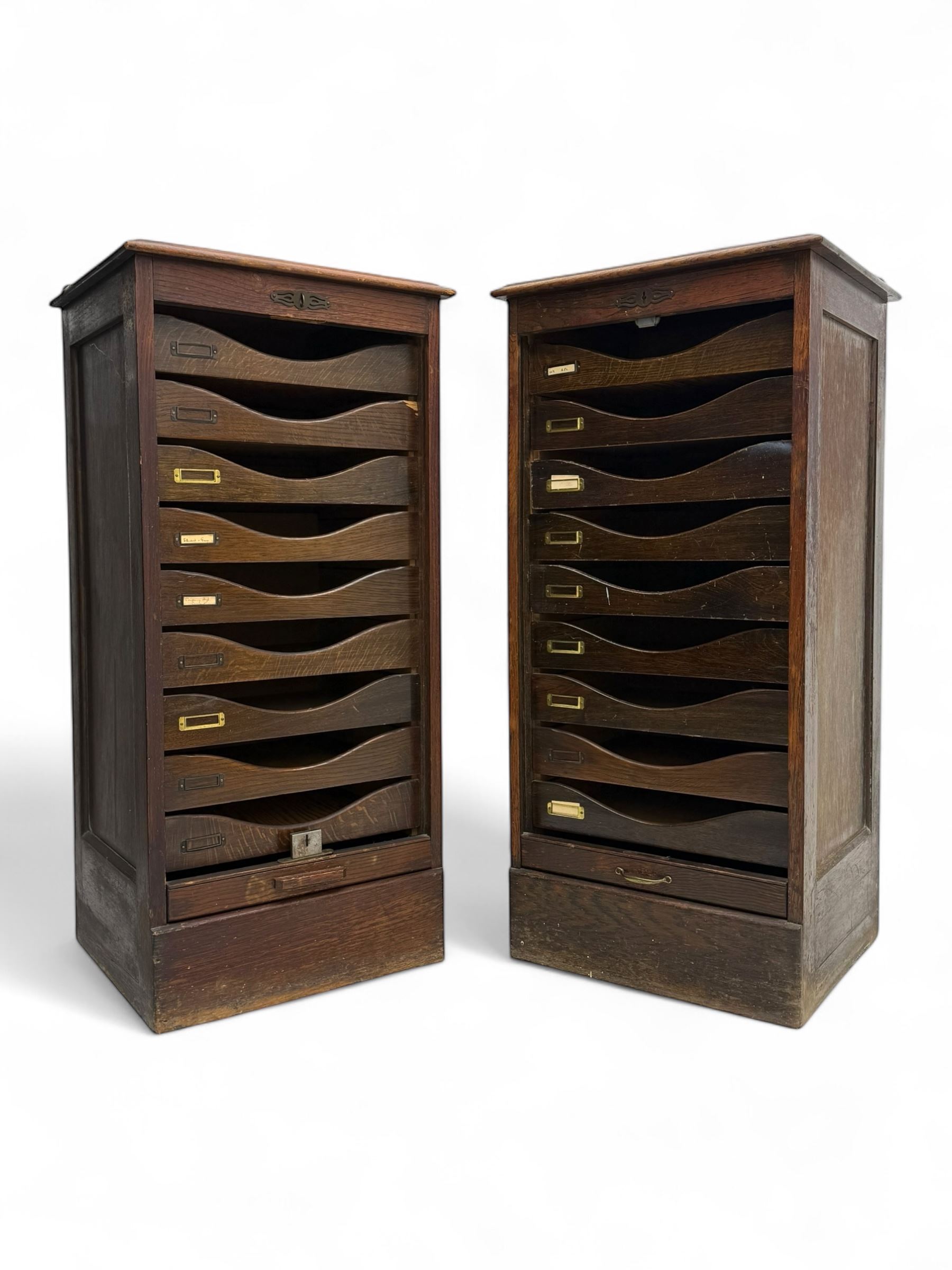 Two early 20th century mahogany tambour cabinets, each with retractable roll-top front revealing fitted interior with concave-front filing drawers and brass fittings
