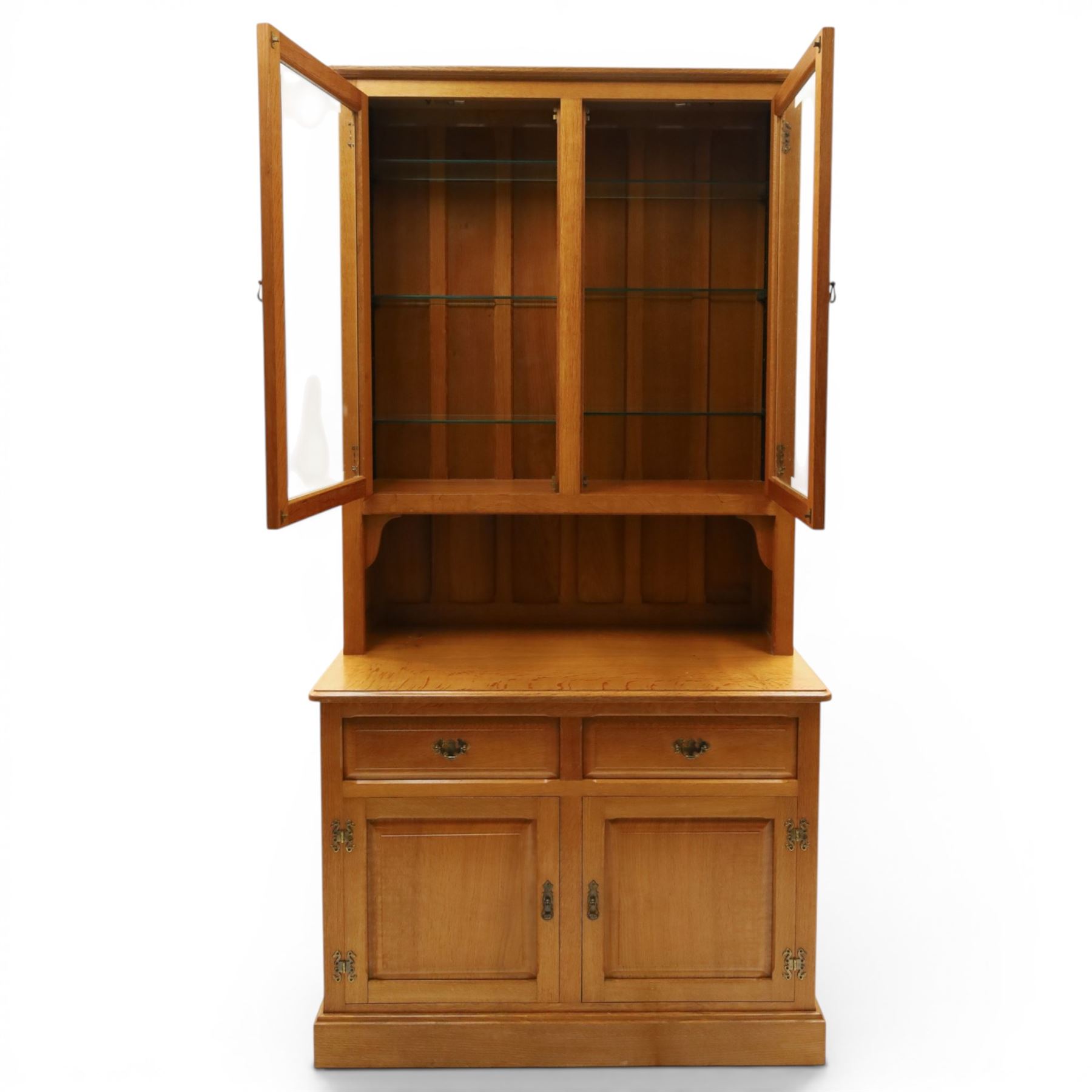 Knightman - oak dresser, the upper section fitted with twin glazed doors enclosing glass shelves, over open recess with panelled back, the base fitted with two drawers over twin panelled cupboards enclosing shelves, with recessed carved knight trademark, by Horace Knight of Old Mill Furniture, Balk near Thirsk
