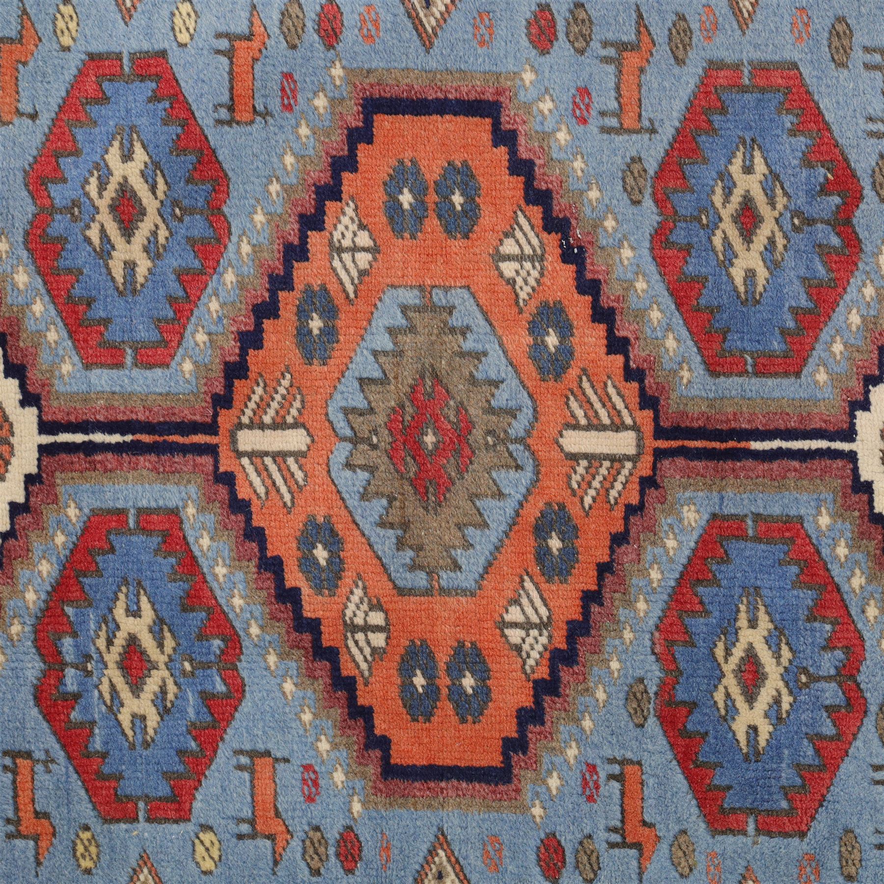 Caucasian Kazak hand-knotted rug, pale blue main field with large geometric medallions in a vertical arrangement and angular tribal motifs within a rosette and geometric border, cotton fringe end, 68x88cm