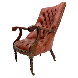 Regency style library chair, upholstered in deeply buttoned red leather, scrolling and moulded arms, on turned front supports with brass castors, studded detail