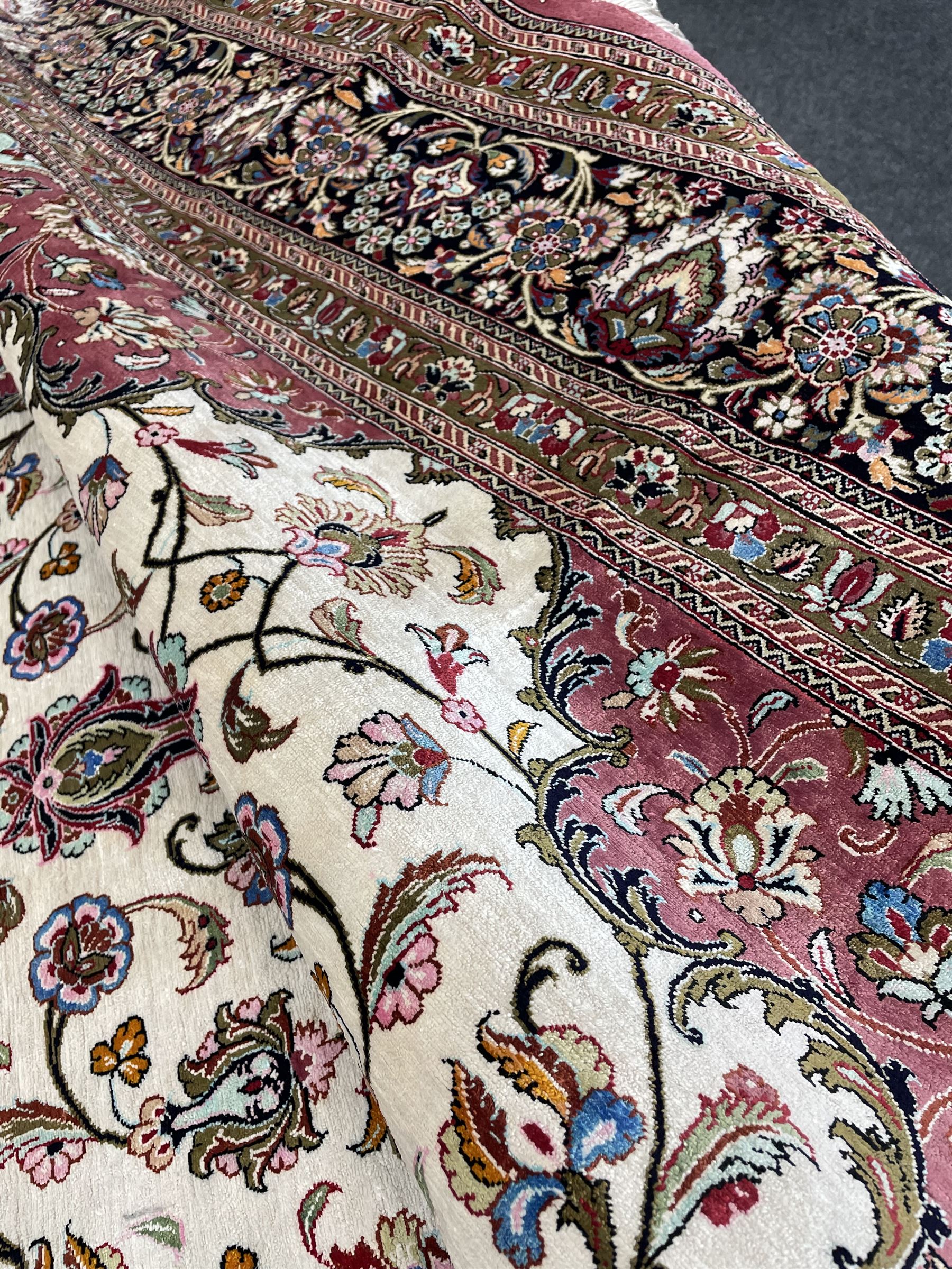 Finely knotted Persian Qom silk rug, overall pink ground with ivory field, the field with central cusped medallion profusely decorated with interlacing foliate and stylised flower heads, multiple band boarder, the main band decorated with a series of stylised motifs and trailing foliage, the outer guard with signature panel 