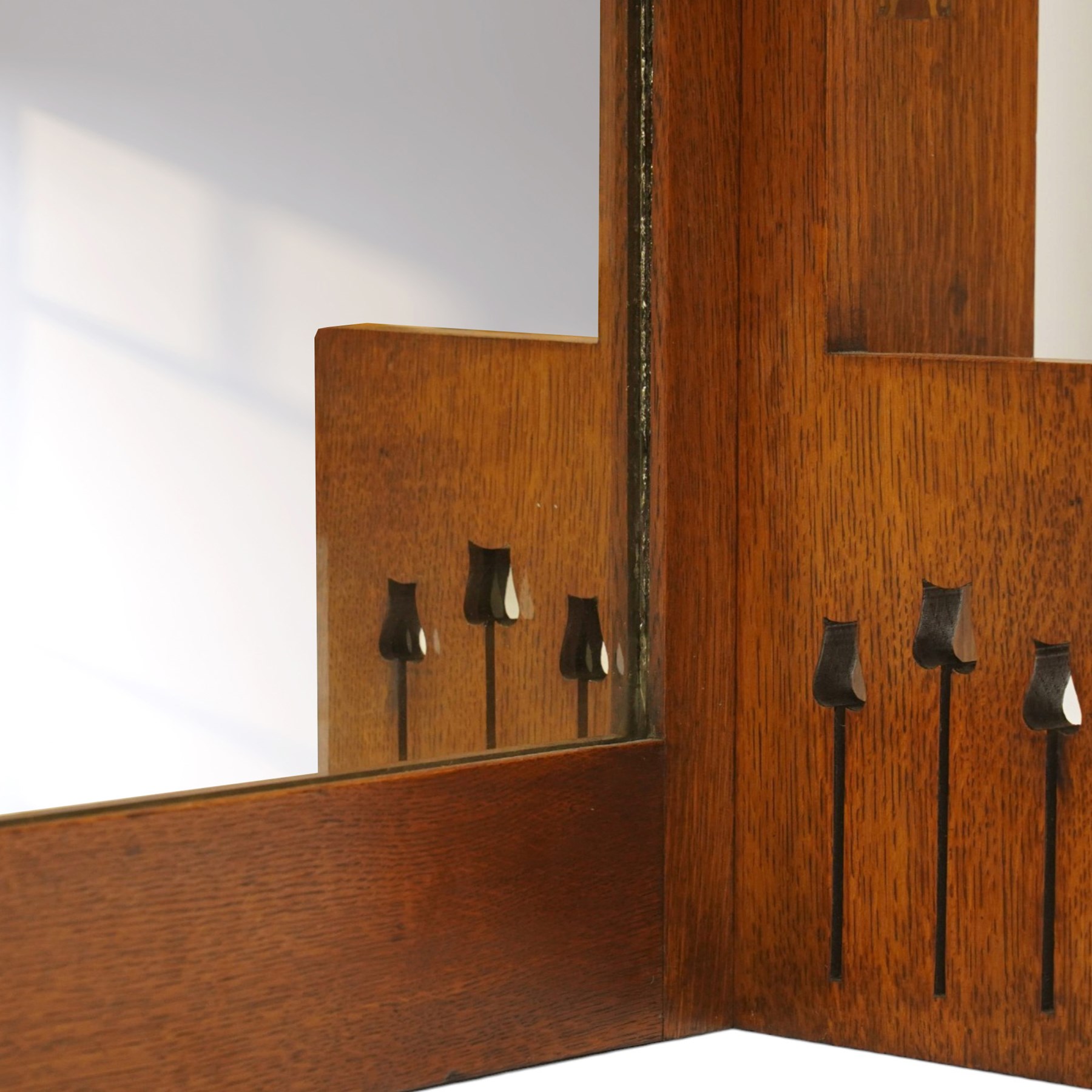 Manner of Liberty & Co, - Arts & Crafts inlaid oak overmantel mirror, the deep-projecting cornice over a rectangular plate, flanked by Art Nouveau marquetry panels of stylised tulip and foliate motifs, over a canted shelf and tulip-pierced upright