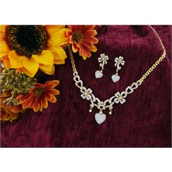 Pair of 18ct gold diamond heart and bow earrings, each stud with a heart shaped pendant, set with round brilliant cut diamonds, suspending from a diamond ribbon and bow motif