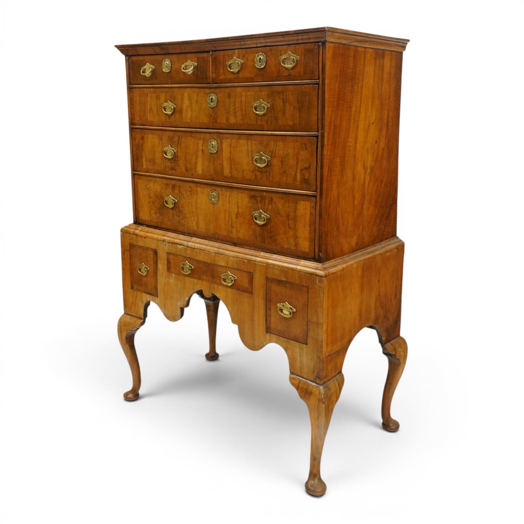George II figured walnut chest-on-stand, the moulded cavetto top over two short and three long graduating cross-banded drawers, each fitted with pressed brass handle plates, the base fitted with three further drawers over a shaped apron, raised on cabriole supports with pad feet