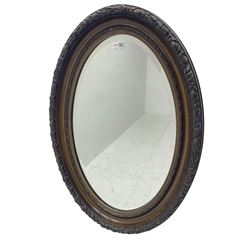 Early to mid-20th century oval wall mirror, the frame decorated with foliate and berries, with bevelled plate