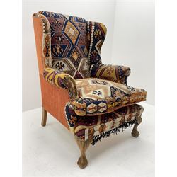 Late 20th century beech framed wingback armchair, sprung seat and back upholstered in kilim cover, acanthus carved cabriole supports with ball and claw feet