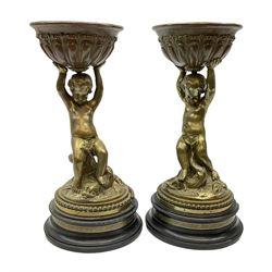Pair of early 20th Century bronze table centre bowls, each modelled as a seated cherub with a grotesque fish at his feet, supporting a bowl with gadrooned and foliate detail, raised upon a stepped circular base, each unsigned, H34cm