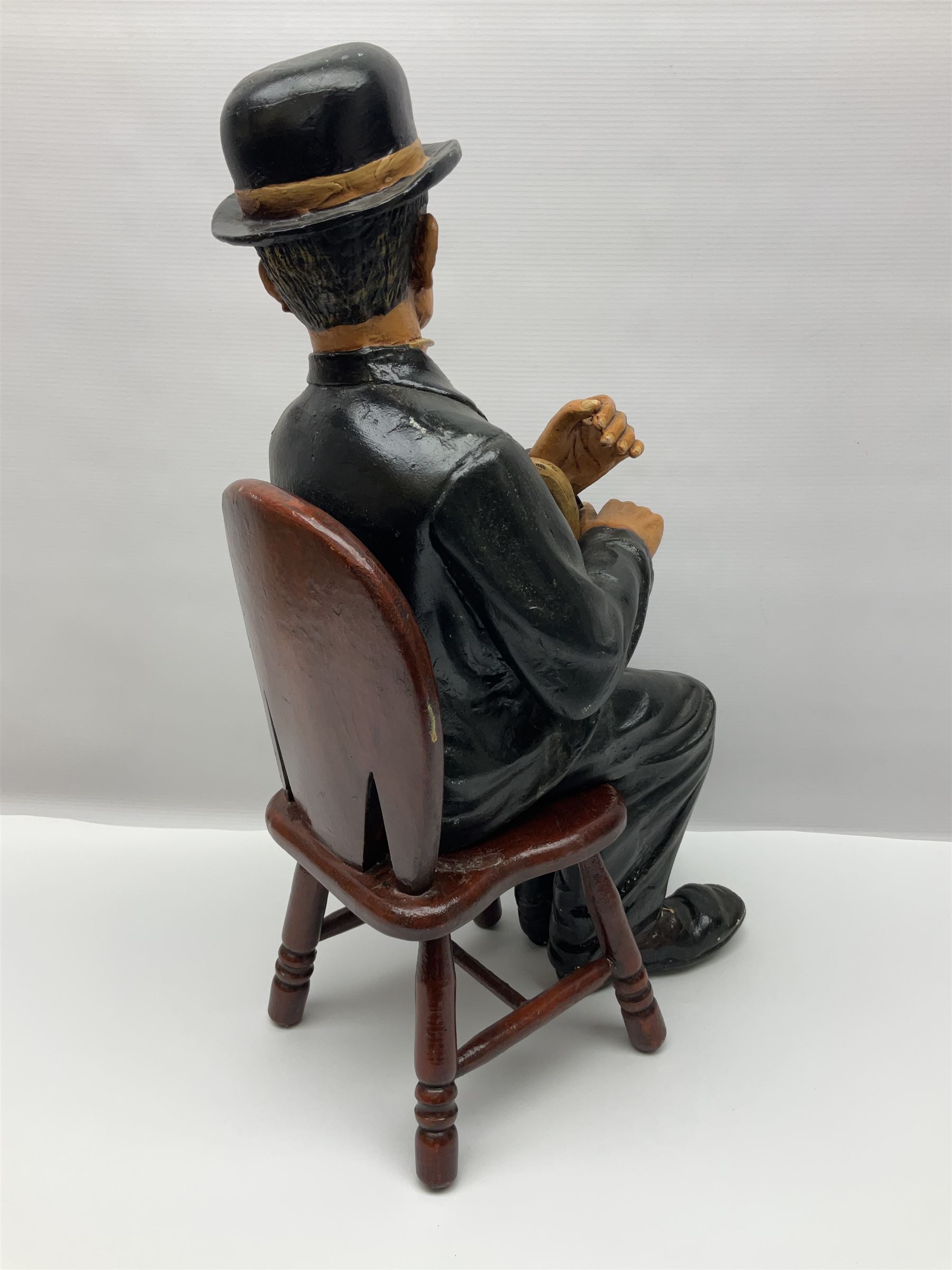 Large painted composite figure of Charlie Chaplin, seated upon wooden chair, H54cm