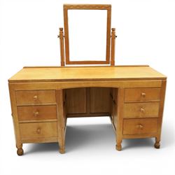 Mouseman - adzed oak kneehole dressing table with mirror, the rectangular adzed top with raised back and canted corners with fixed central pivoting mirror with scallop-carved cresting rail, over an arched recessed kneehole flanked by three graduating drawers to each side with turned knob handles, raised on octagonal feet, with carved mouse signature, by the workshop of Robert Thompson of Kilburn