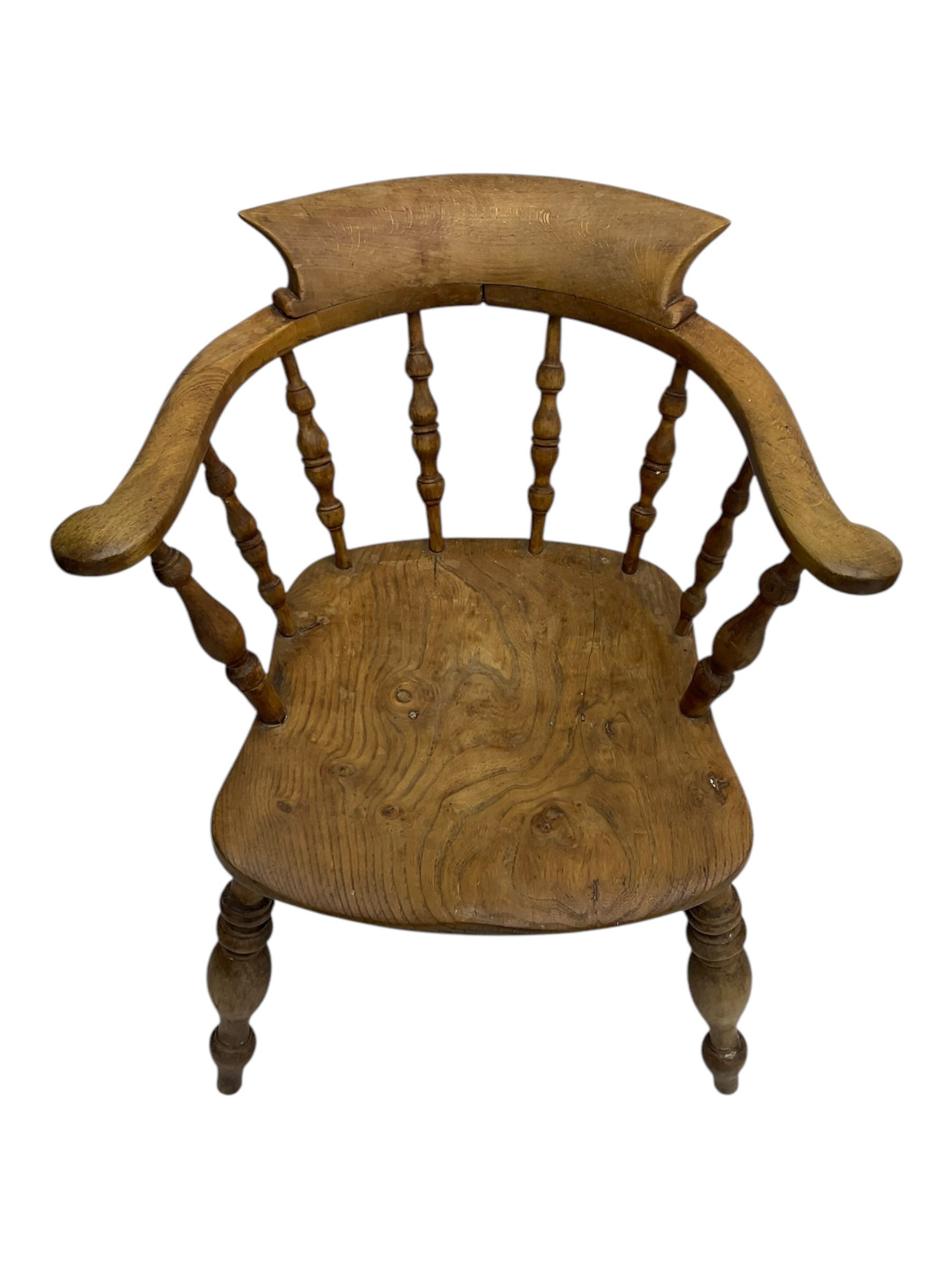 Late 19th century elm smoker’s bow armchair, curved top rails over turned spindle backs, shaped seats, raised on turned legs united by turned stretchers; together with a similar smoker’s bow armchair (2)
