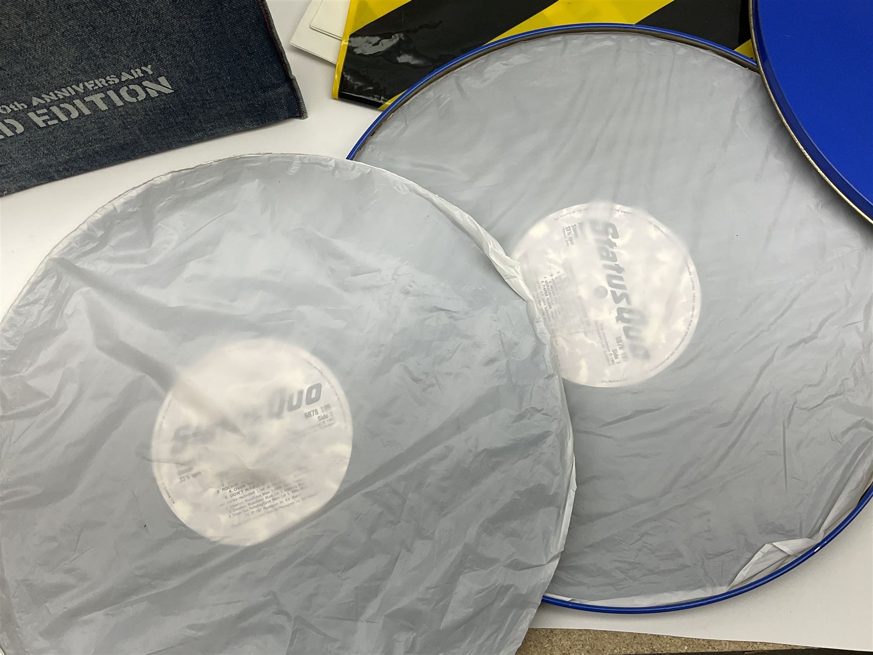 Status Quo: The Official 40th Anniversary Limited Edition book No.926/3000 with certificate signed by Rossi and Parfitt. Duplicate signatures by Rossi and Parfitt on pages within the book. Denim dustjacket; 'From The Makers Of ....' boxed set of three LP records in circular blue tin; and quantity of tour carrier bags