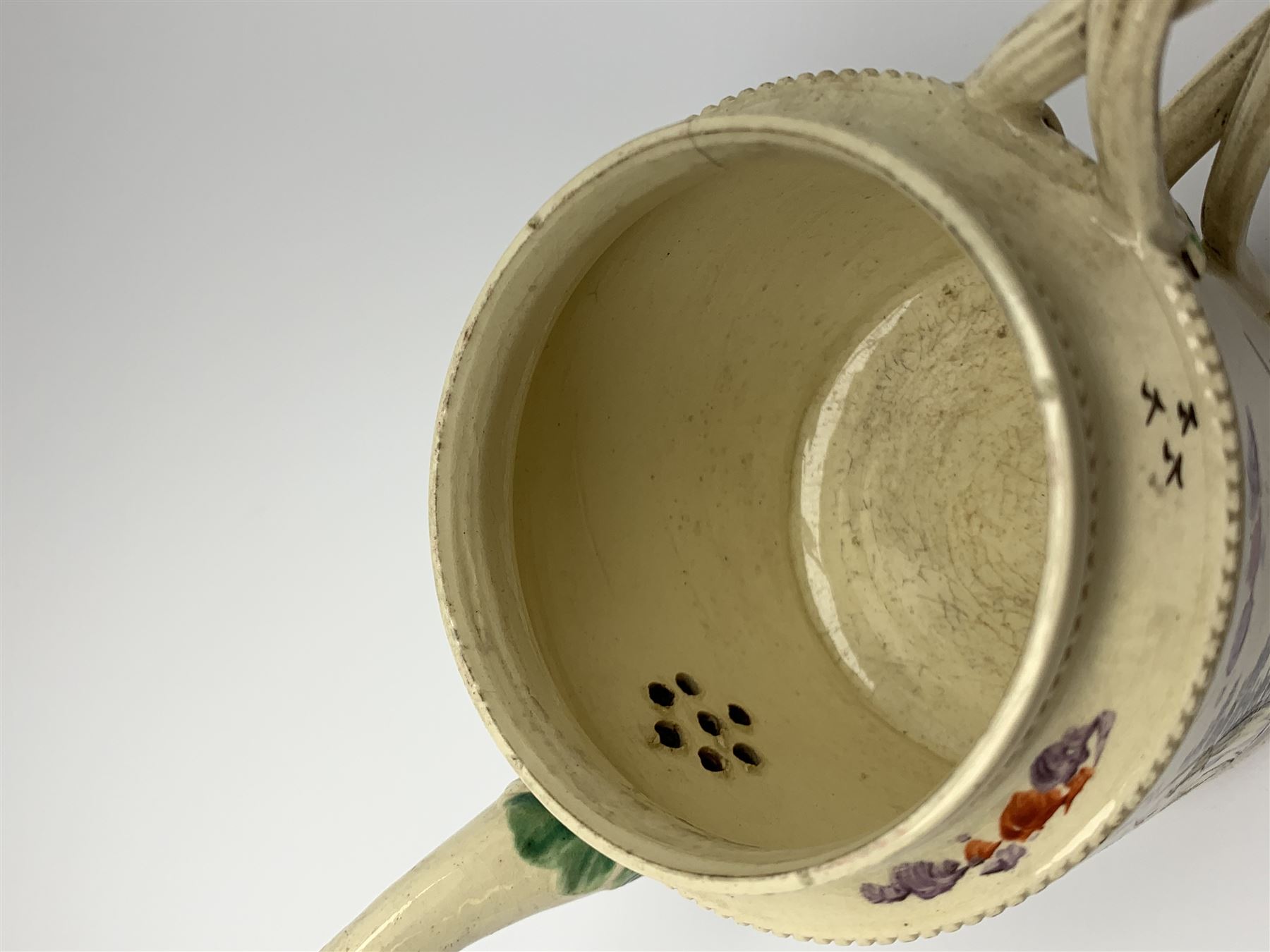 18th century creamware teapot, probably Leeds, with reeded entwined handle and floral finial to the cover, the body with hand painted polychrome decoration of figure to one side, and floral spray to the other, collectors paper label beneath inscribed Leeds Pottery, H11.5cm