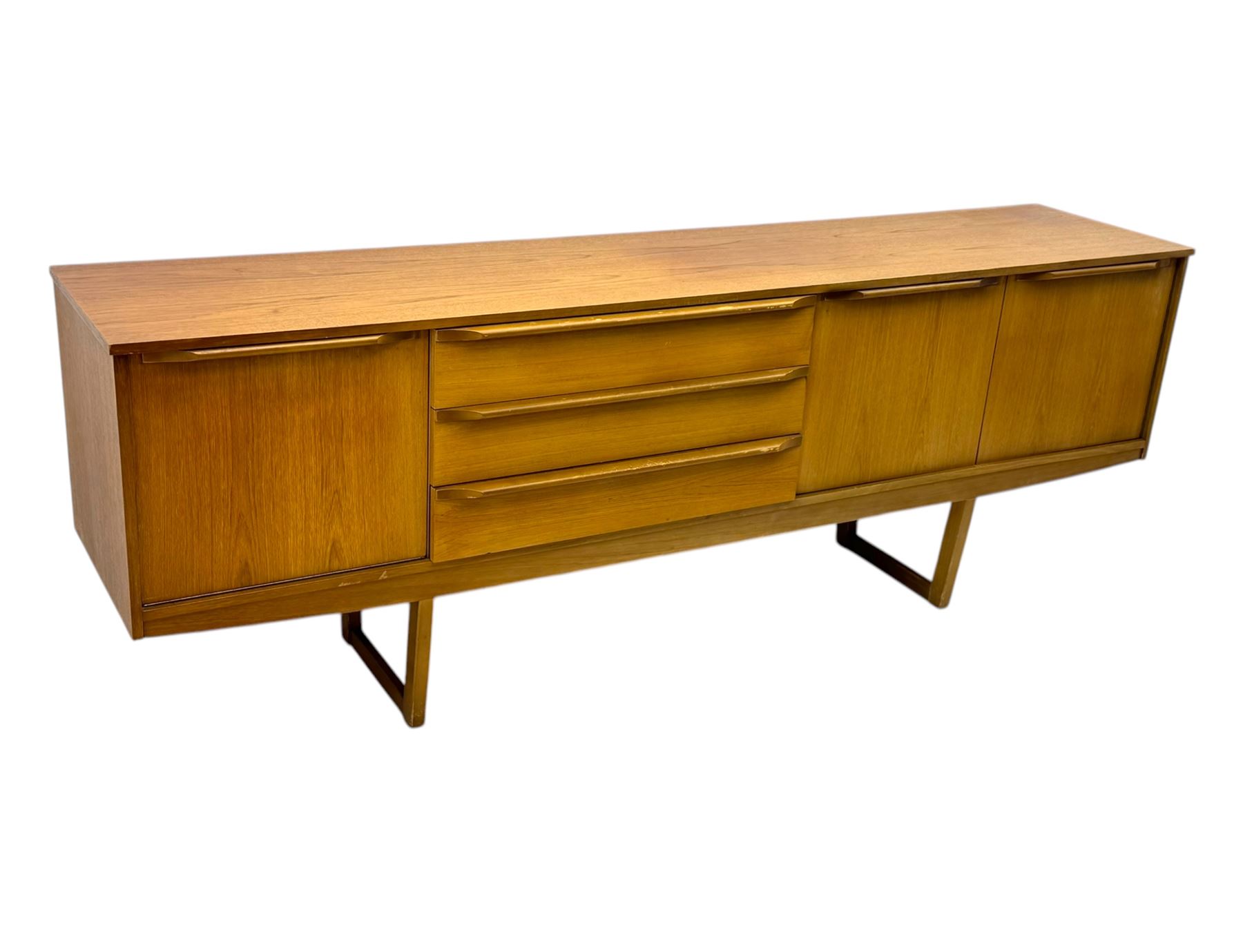 Mid-20th century teak sideboard, fitted with a fall-front cupboard, three drawers including a green baize-lined cutlery drawer, and a double cupboard, with integrated handles, on sleigh supports