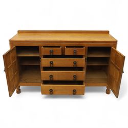 Mouseman - oak sideboard with adzed top and raised gallery back, over two short drawers and three long drawers, flanked by panelled cupboard doors with wrought iron fittings, on octagonal feet, carved with the signature mouse to the right-hand door