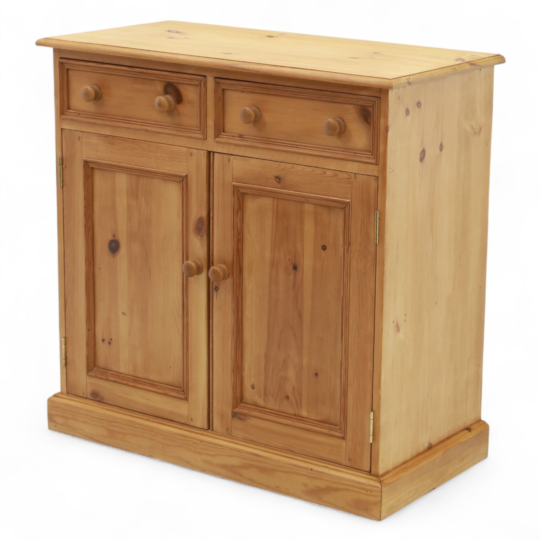 Contemporary pine storage cabinet, the rectangular top with rounded corners, over twin drawers and panelled cupboard doors, fitted with turned knob handles, plinth base