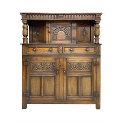 Jacobean design oak court cupboard, upper section with carved arched panelled cupboard door flanked by turned columns, beneath carved and moulded frieze, lower section fitted with two drawers over two cupboard doors with gothic arched panel decoration, raised on stile supports