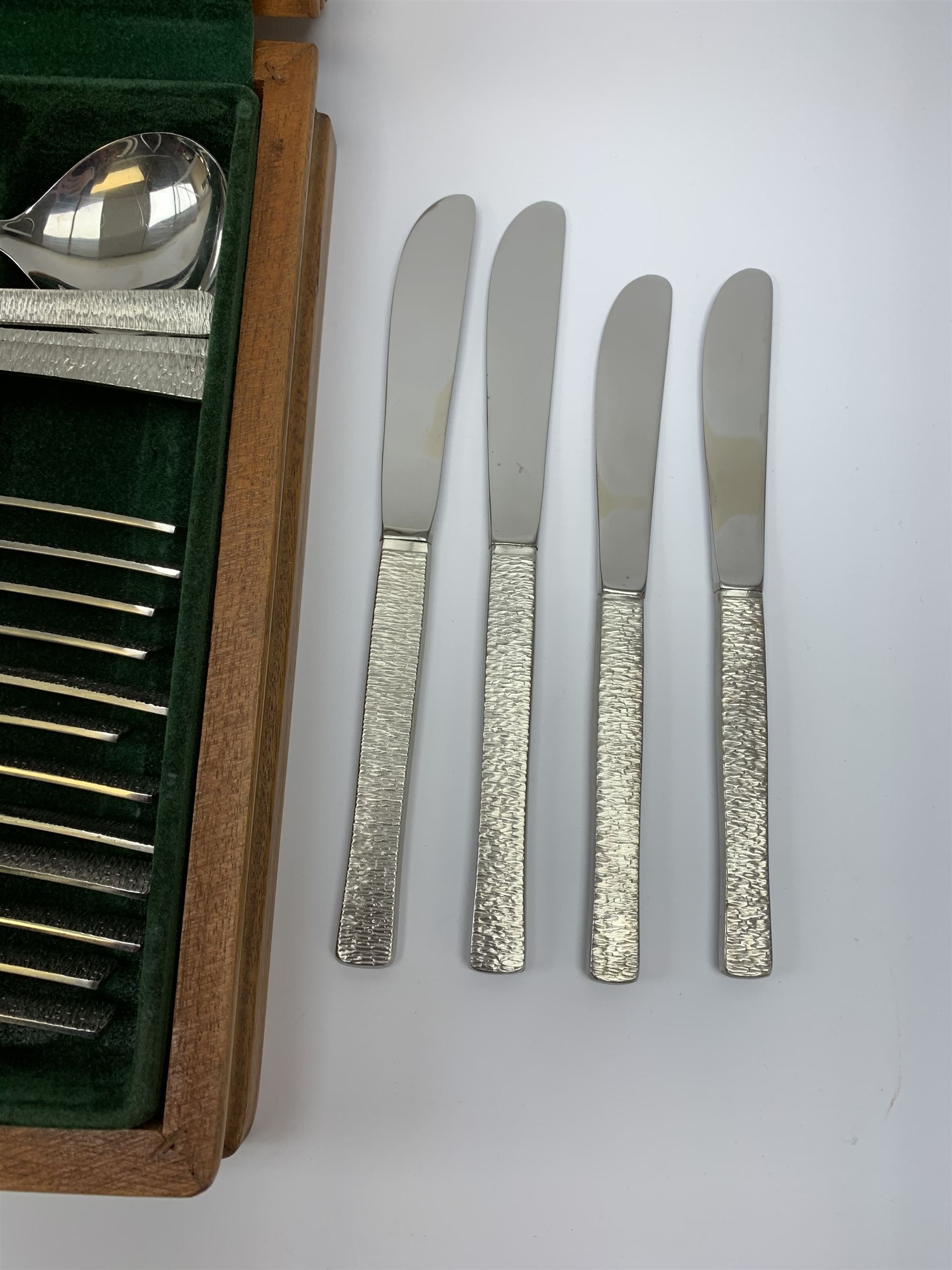 A canteen of bark effect stainless steel cutlery by Gerald Benney for Viners Studio, in a teak case. 
