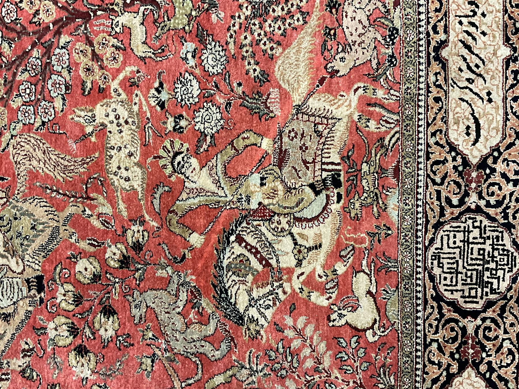 Fine Persian silk and cotton hunting rug, pink ground field depicting hunting scenes, trees and flowers, the border decorated with scrolls and script panel