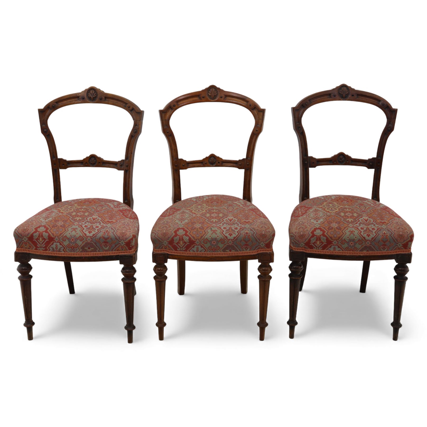 Set of six late Victorian mahogany dining chairs, the shaped top rails carved with anthemion motifs, above pierced splats, floral and geometric fabric seat, on turned and fluted front legs