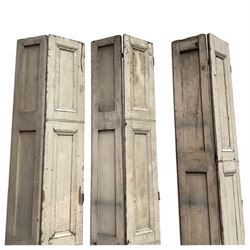 Set of three French 19th century painted pine folding window shutters of tall form, each comprising two hinged leaves with three graduated raised and fielded panels, in antique cream-painted finish