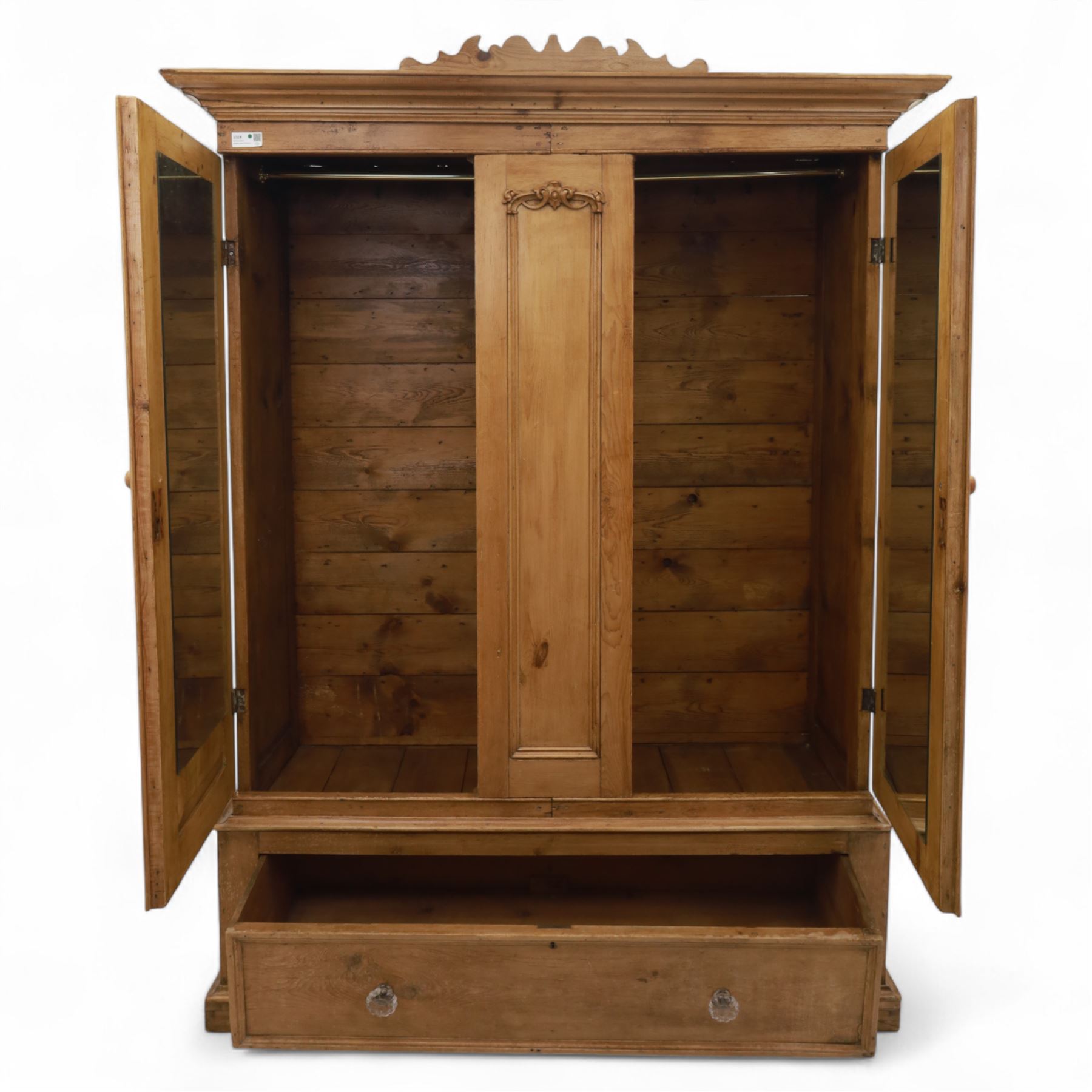 Late 19th century pine wardrobe, with stepped cornice over triple panelled doors, applied foliate carvings to outer panels, raised over a separate pine plinth drawer with moulded facia and twin glass pulls
