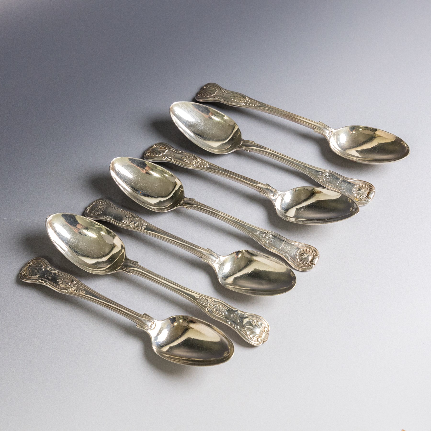 Seven silver Kings/Queens pattern dessert spoons, including George III Irish silver pair with engraved griffin crests, hallmarked Dublin 1818, maker's mark SI and five with varying dates and makers, all hallmarked 
