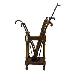 Early 20th century oak stick stand, rectangular structure with decorative carving, square base fitted with tray, on turned supports topped with finials; twelve assorted walking canes 