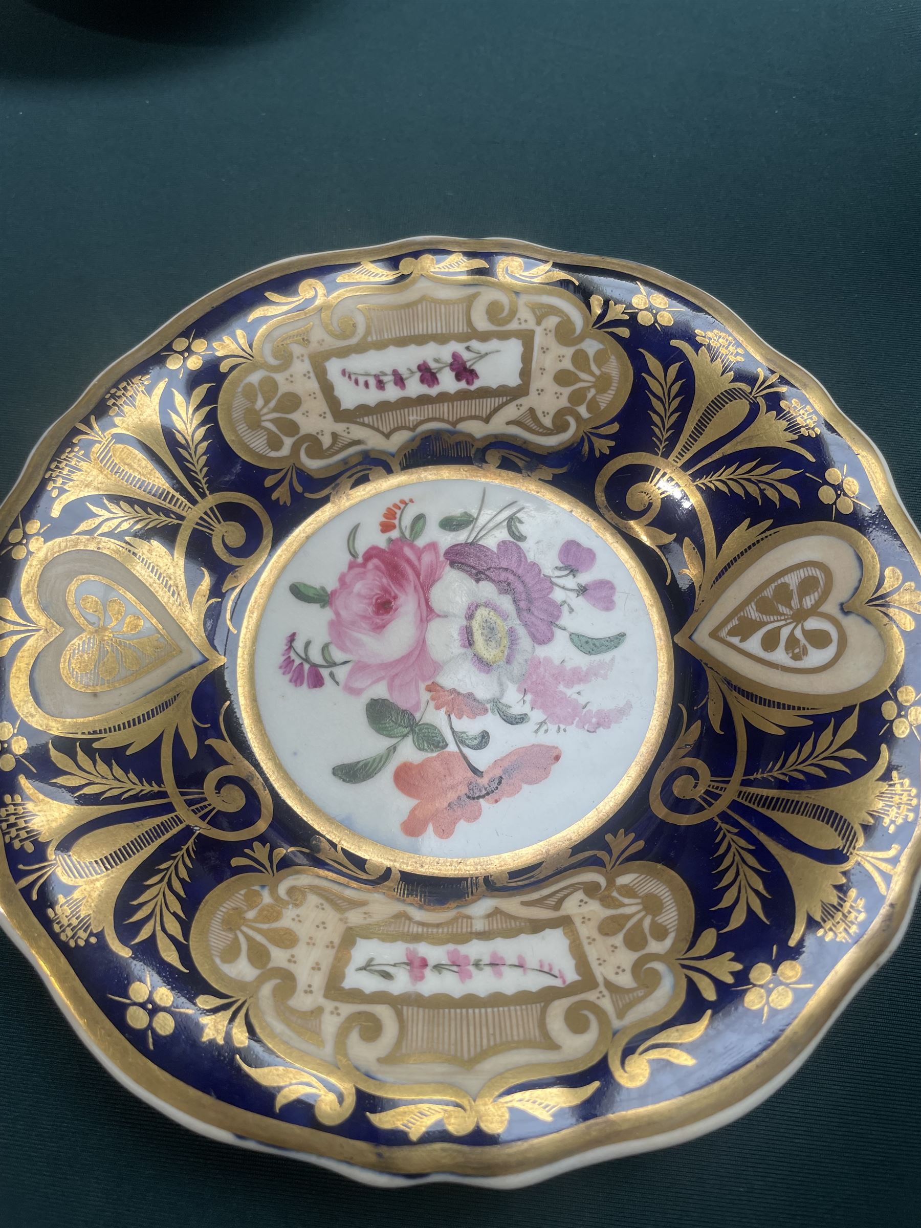 19th century teacup and saucer, possibly Coalport, decorated with panels of flowers on a cobalt blue ground with gilt decoration; together with two other teacup and saucer pairs, one with hand painted landscape decoration 