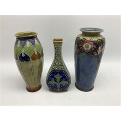 Two Royal Doulton stoneware vases, the first example with tubelined floral decoration, the second with Art Nouveau decoration, together Doulton Lambeth vase of flattened form with foliate decoration on a green ground, all with impressed mark beneath, tallest example H26cm
