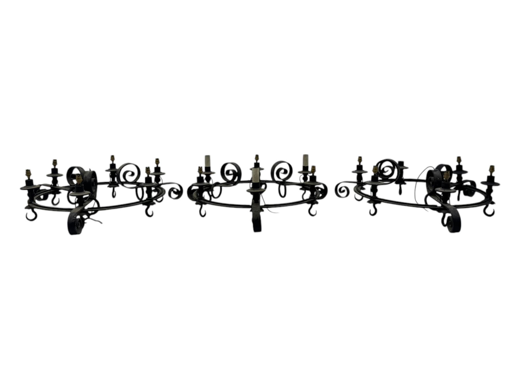 Set of three mid-20th century wrought iron six-light chandeliers, each with a circular frame with scrolled arms, faux candle sleeves and hook terminals