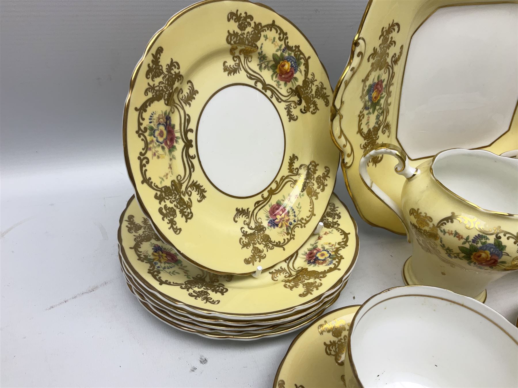 Aynsley tea service for six, decorated with floral sprays in ornate gilt detailing on cream ground, comprising six teacups and saucers, open sucrier and milk jug and cake plate, all with printed marks beneath