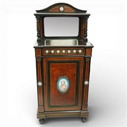 Victorian Aesthetic Movement amboyna and ebonised cabinet, the arched raised back inlaid with amboyna and floral porcelain plaque, over a raised shelf with fluted and turned supports, and a bevelled mirror plate with brass beading beneath, the inverted-breakfront top over an ornate frieze drawer with guilloche style gilt-metal mounts and porcelain plaques, the panelled door with a central porcelain plaque depicting a lady in a fuchsia gown within concentric ebonised and amboyna inlays, flanked by architectural style uprights with Corinthian capitals, raised on turned feet