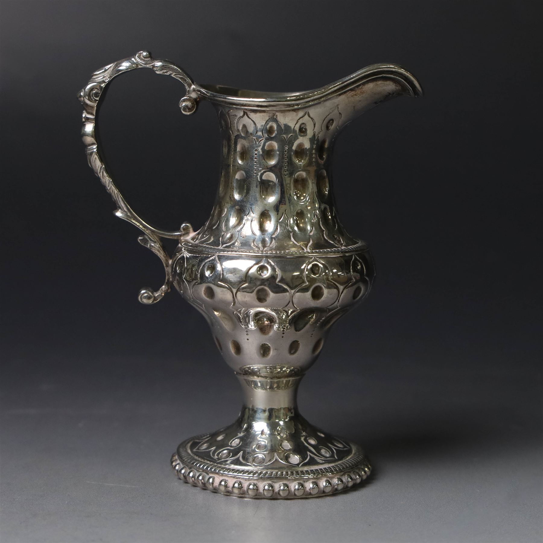 George III silver cream jug, of baluster form with hammered dimpling throughout and scroll handle, upon circular spreading foot with beaded edge, hallmarked Thomas Shepherd, London 1784, H10cm