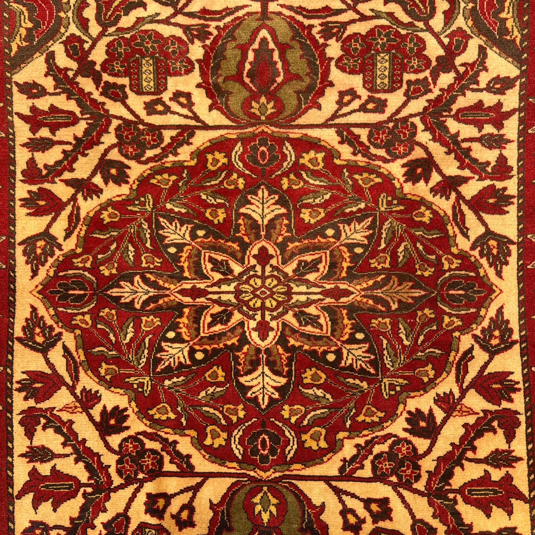 Persian Kerman hand-knotted rug, ivory and crimson ground, central medallion surrounded  by a floral foliate pattern, main border with repeating design of floral cartouches and palmettes, and narrow vine work guard border  