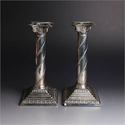 Pair of Edwardian silver mounted column candlesticks, each with embossed floral, foliate and scrolling decoration and upon stepped square weighted bases, hallmarked William Hutton & Sons Ltd, London 1901, H19cm