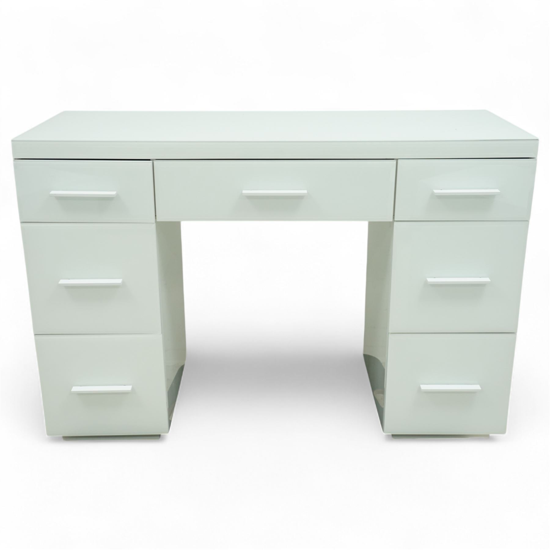 Contemporary white and glass twin pedestal dressing table and two matching bedside chests, dressing table with rectangular top above seven flush-front drawers arranged around a central kneehole, with white matching pulls, bedside chests each with square top over three drawers with integrated handles, plain sides and plinth bases

Bedside tables (W 121cm D 41cm H 82cm)
Dressing table (W 45cm D 45cm H 66cm)