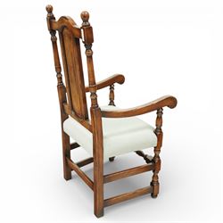 Country House oak high back dining chairs, set of ten comprising eight side chairs and two carvers, each with arched top rail flanked by turned finials over a central fielded panel back, with overstuffed seats upholstered in pale fabric, raised on turned front supports united by stretchers