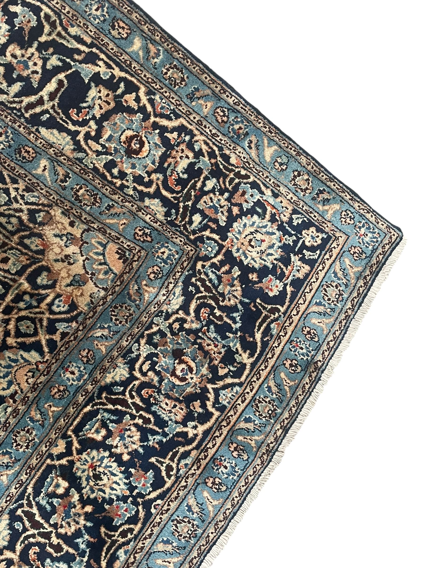 Persian Kashan indigo ground rug, the rosette medallion decorated with projecting palmettes, on a field of swirling leafy branches and decorated with further palmettes, the scrolling border with repeating stylised plant motifs, within floral pattern guard stripes