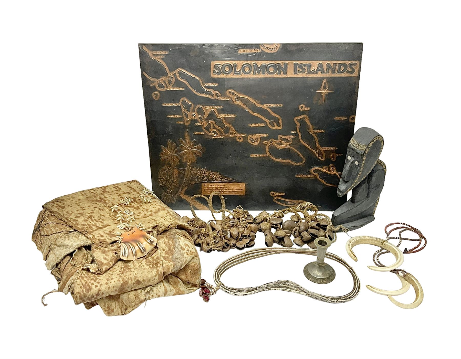 Collection of traditional necklaces from the Solomon Islands, including shell and boar tusk examples, together with a carved canoe prow, with mother of pearl eyes, painted cow hide and a copper plaque, depicting the Solomon Islands, with presentation engraving