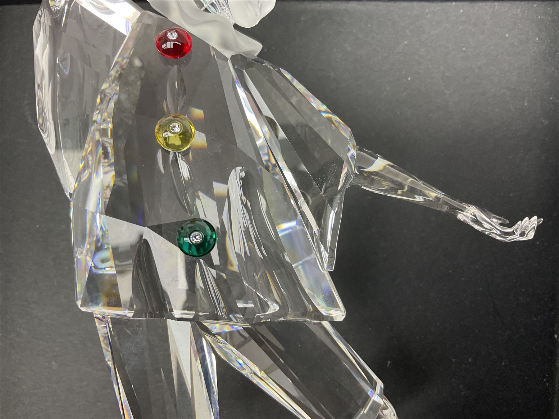 Swarovski Crystal Masquerade trilogy; 1999 Masquerade Pierrot, 2000 Columbine, 2001 Harlequin all with accompanying plaque, stand and original box, together with a glass display case with mirrored back and sides 