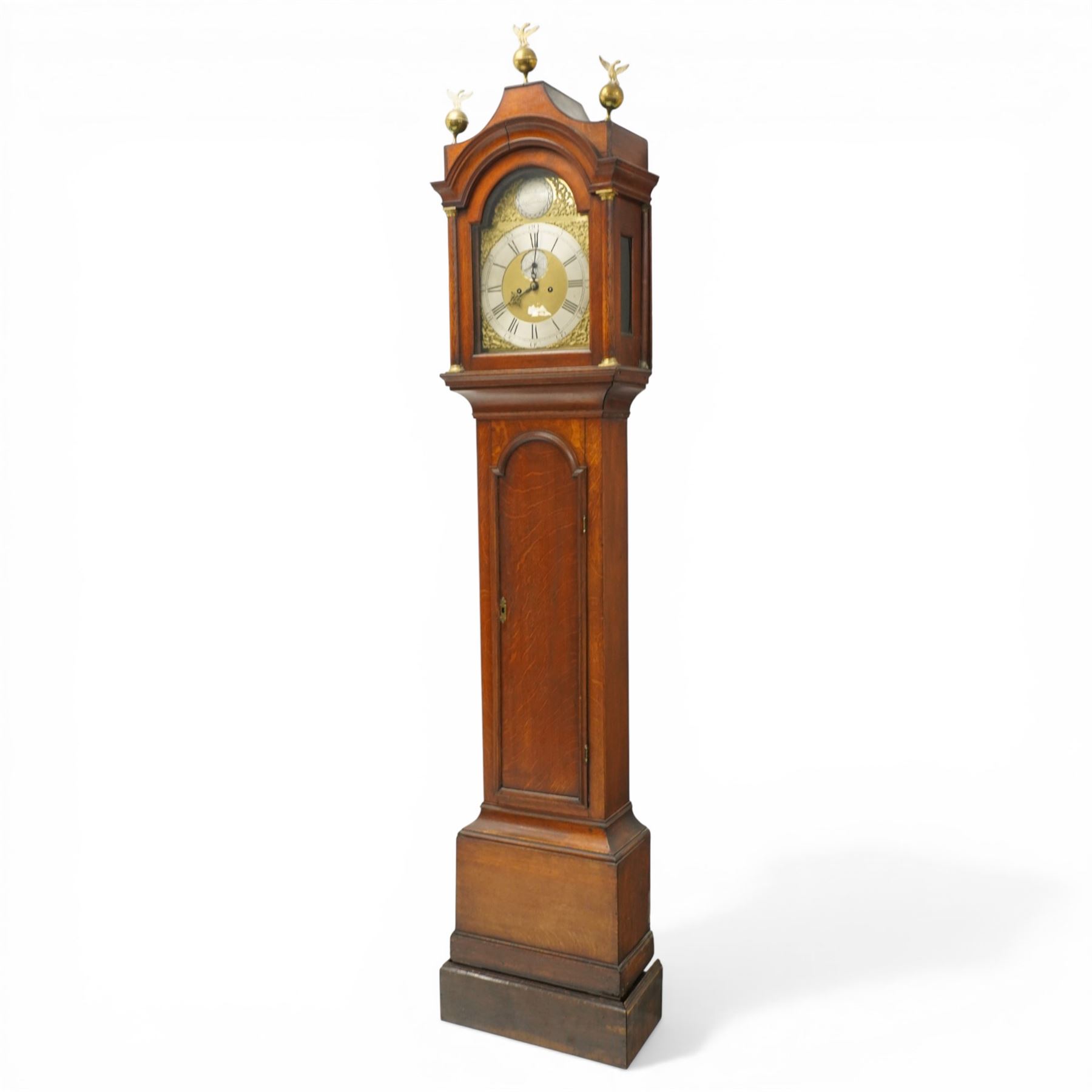 18th century oak eight-day longcase clock,  signed James Smyth, Saxmundham, the arched hood with brass ball and eagle finials, moulded arch pediment over turned columns, brass dial with silvered Roman chapter ring, Arabic minute track, matted centre with subsidiary seconds dial and calendar aperture, engraved boss to arch, the trunk with arched panel door, on stepped plinth base, with two weights and pendulum